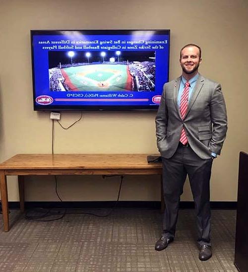 Professor Caleb Williams stands with a television depicting a Moroccan soccer game