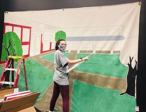 savanna hicks paints a backdrop for her play.